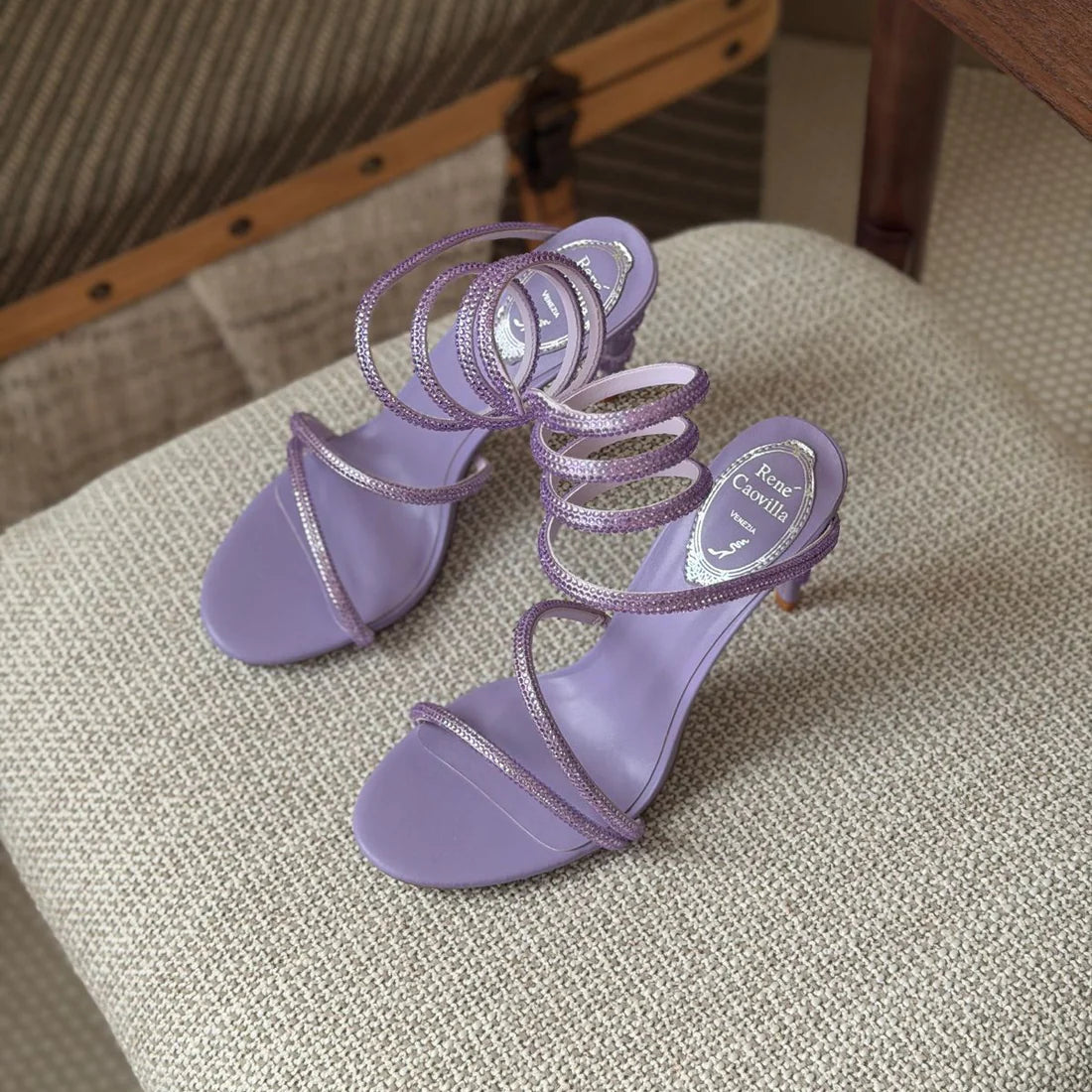 Pair of purple high-heeled sandals on a textured surface