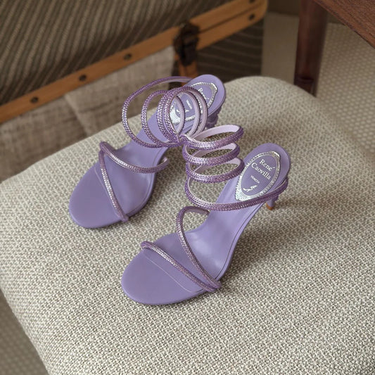 Pair of purple high-heeled sandals on a textured surface